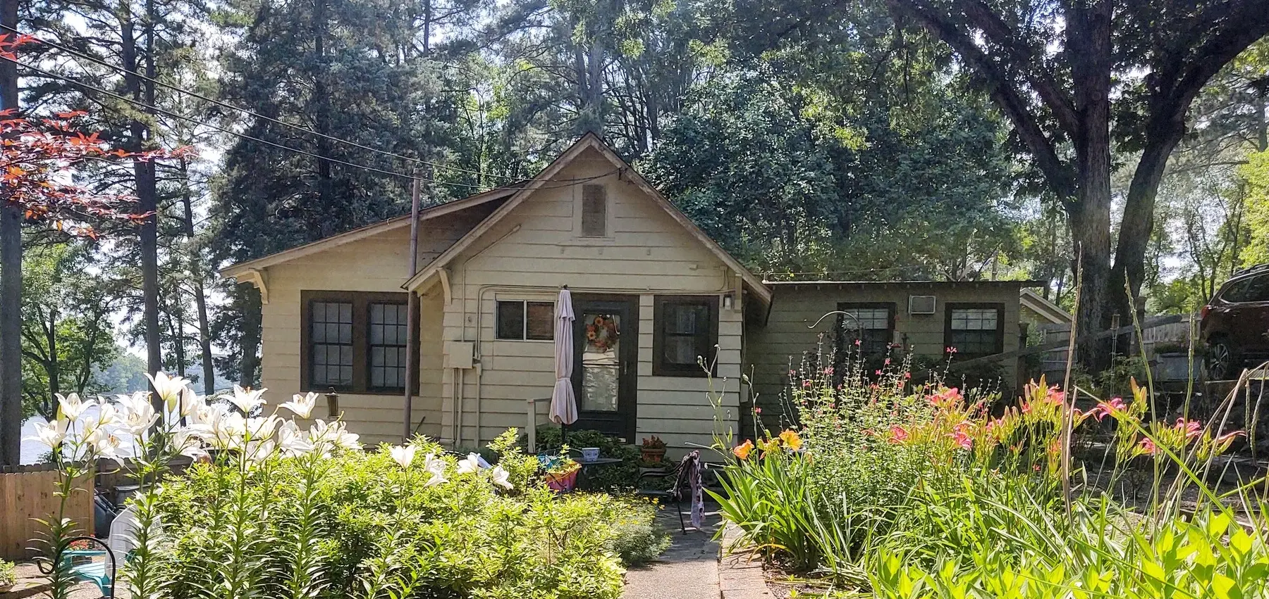 Cottage at the end of a sidewalk and set amongst the trees